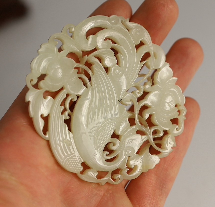 A Chinese white jade ‘phoenix and peony’ reticulated plaque, early 19th century, 6.9cm wide, wood stand